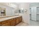Bathroom with double sinks, wood cabinets, large mirror, and walk-in closet access at 4808 E Betty Elyse Ln, Scottsdale, AZ 85254