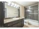 Well-lit bathroom with granite counters, a large mirror, and a shower-tub combo with glass doors at 5345 E Van Buren St # 305, Phoenix, AZ 85008