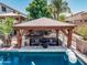 Gazebo with comfortable seating, a fire table, and views of the pool, perfect for outdoor relaxation and entertainment at 551 E Sun Valley Farms Ln, San Tan Valley, AZ 85140