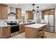 Modern kitchen features wood cabinetry, stainless steel appliances, white countertops, and a stylish island with seating at 635 N 67Th Pl, Mesa, AZ 85205