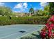 A private tennis court showcases manicured hedges with views of mountains, palm trees, and red flowers at 6624 N 66Th N Pl, Paradise Valley, AZ 85253