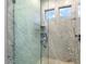 Close up of shower with marble tile, glass doors, and chrome fixtures at 7222 E Gainey Ranch Rd # 241, Scottsdale, AZ 85258