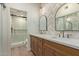 Modern bathroom showcasing double sinks, wood cabinets, decorative mirrors, and a glass enclosed shower at 7710 E Gainey Ranch Rd # 142, Scottsdale, AZ 85258