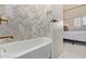 Beautiful bathroom with a tub featuring unique herringbone tile, and views into the bedroom at 7710 E Gainey Ranch Rd # 142, Scottsdale, AZ 85258
