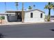 Exterior view of a manufactured home featuring a carport, desert landscaping, and a light-colored facade at 7807 E Main St # G-23, Mesa, AZ 85207