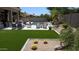 Inviting backyard featuring a pool, lush landscaping, an outdoor seating area, and artificial grass at 7940 E Quill Ln, Scottsdale, AZ 85255