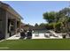 Spacious backyard with a sparkling pool, lush lawn, covered patio, and seating areas at 7940 E Quill Ln, Scottsdale, AZ 85255