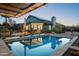 Stunning backyard features a sparkling pool reflecting the home and evening sky, with outdoor seating at 8037 E Krail St, Scottsdale, AZ 85250