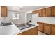 Bright kitchen features light countertops, stainless steel sink and plentiful wood cabinetry, tile floor and natural light at 8101 E 4Th Ave, Mesa, AZ 85208