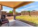 A well-used backyard featuring a covered patio, brick fence, and a grass yard with play equipment at 13022 W Cherry Hills Dr, El Mirage, AZ 85335