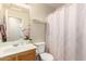 Standard bathroom with a white toilet, a wood vanity, and a shower with a patterned curtain at 13022 W Cherry Hills Dr, El Mirage, AZ 85335