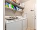 Laundry room with a white washer and dryer, storage shelves, and tile flooring at 13022 W Cherry Hills Dr, El Mirage, AZ 85335