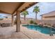 Backyard oasis with a pool, spa, rock waterfall, palm trees and covered patio at 15809 S 31St St, Phoenix, AZ 85048