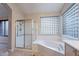 Clean bathroom featuring a glass-enclosed shower and a soaking tub with a unique glass block window at 15809 S 31St St, Phoenix, AZ 85048