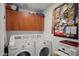 A laundry room with cherry wood cabinetry, stacked front-load laundry, and decorated cork board at 17 W Vernon Ave # 31, Phoenix, AZ 85003