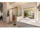 Relaxing primary bathroom featuring a soaking tub, separate shower, and views of the backyard at 1802 W Encinas St, Gilbert, AZ 85233