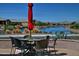 Lakeside patio seating area with a table, chairs, red umbrella, and picturesque water views at 20211 N Winter Escape Ct, Maricopa, AZ 85138