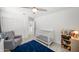 Well-lit bedroom with neutral walls, a ceiling fan, carpet floors, and a crib at 20872 W Thomas Rd, Buckeye, AZ 85396