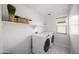 Well-lit laundry room offers modern machines, neutral colors, decor, and a storage shelf above machines at 20872 W Thomas Rd, Buckeye, AZ 85396
