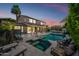 Twilight view of the backyard featuring a sparkling pool, spa, travertine tile, and outdoor lounge area at 2282 E Zion Way, Chandler, AZ 85249