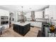 Bright kitchen features a black island with seating, white cabinets, stainless steel appliances, and modern pendant lighting at 2282 E Zion Way, Chandler, AZ 85249