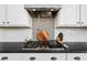 Kitchen gas stovetop with patterned backsplash, hood, and white cabinets at 2282 E Zion Way, Chandler, AZ 85249