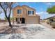 Two-story tan home featuring a two-car garage, a covered porch, and manicured landscaping at 23772 W Grove St, Buckeye, AZ 85326