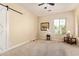 Bright, carpeted bedroom featuring a window, ceiling fan and a barn door at 2457 E Melrose St, Mesa, AZ 85213