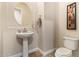 Elegant powder room featuring a pedestal sink, oval mirror, and stylish decorative wall art at 2457 E Melrose St, Mesa, AZ 85213