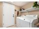 Bright laundry room with a white washer and dryer, shelving and tiled floors at 25806 W Hilton Ave, Buckeye, AZ 85326