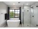 Serene bathroom featuring a freestanding tub, walk-in shower with glass enclosure, and a window offering natural light and views at 2604 N 27Th St # 4, Phoenix, AZ 85008