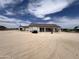 An exterior of a one-story white home with a brown roof and a detached garage situated on a large gravel lot at 29935 W Roosevelt St, Buckeye, AZ 85396