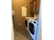 The laundry room features a washer, dryer, overhead cabinet, and a mop in a room with brown walls at 29935 W Roosevelt St, Buckeye, AZ 85396