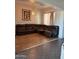 An indoor living room with a brown, L-shaped couch, mixed flooring, and a hanging light fixture at 29935 W Roosevelt St, Buckeye, AZ 85396