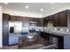 Modern kitchen boasts stainless steel appliances, dark wood cabinets, a stylish backsplash, and an island with a granite countertop at 3113 E Danbury Rd # 10, Phoenix, AZ 85032
