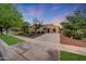 Charming home exterior features desert landscaping, mature trees, and a spacious driveway at dusk at 3467 N Hooper St, Buckeye, AZ 85396