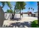 Paved backyard area featuring a stucco wall, privacy fence, and lush trees providing shade on a sunny day at 3646 W Brown St, Phoenix, AZ 85051
