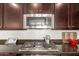 Close-up of a modern gas cooktop with stainless steel microwave and dark wood cabinets at 3783 E Stiles Ln, Gilbert, AZ 85295