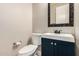 A half-bathroom featuring a blue vanity, decorative mirror, and updated fixtures for a modern aesthetic at 3824 E Parkside Ln, Phoenix, AZ 85050