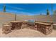Outdoor kitchen area with stone counters, stainless steel BBQ grill, and a desert setting at 3824 E Parkside Ln, Phoenix, AZ 85050