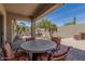 Outdoor living area with round patio table, chairs, lush landscaping, and desert trees at 3824 E Parkside Ln, Phoenix, AZ 85050