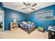 A colorful bedroom with blue walls, ceiling fan, window, bed, and fun decorations at 4136 W Hearn Rd, Phoenix, AZ 85053