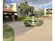 Manicured community grounds with a water fountain, mature trees and lush green grass on a partly cloudy day at 4201 E Camelback Rd # 51, Phoenix, AZ 85018