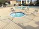 Community hot tub and lounge chairs with a wrought iron fence and tiled perimeter at 4201 E Camelback Rd # 51, Phoenix, AZ 85018