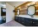 Elegant bathroom featuring a stylish wood accent wall, modern vanity, and oval mirrors at 4201 W Hatcher Rd, Phoenix, AZ 85051