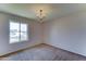 A basic bedroom features neutral carpet, a modern chandelier, and a window at 4201 W Hatcher Rd, Phoenix, AZ 85051