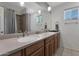 Bright bathroom featuring double sinks, a large mirror, modern lighting, and a shower with tile surround at 4304 W Calle Poco --, Laveen, AZ 85339
