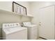 Laundry room featuring a washing machine and dryer with overhead storage shelves at 6781 W Lone Cactus Dr, Glendale, AZ 85308