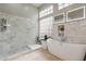 Bright bathroom with marble walls, dual mirrors, a walk-in shower, and a standalone tub at 9678 E Voltaire Dr, Scottsdale, AZ 85260