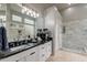 Luxurious bathroom featuring a black marble countertop, glass block windows, and a walk-in shower at 9678 E Voltaire Dr, Scottsdale, AZ 85260